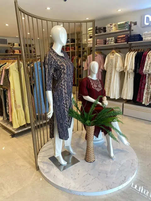 Vismay Chennai: mannequins on a marble plinth framed by a curved brass-finish screen